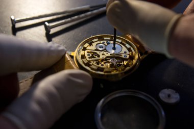 Saatçi antika bir otomatik saati tamir ediyor..