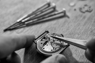 Saatçi antika bir otomatik saati tamir ediyor..