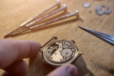 Saatçi antika bir otomatik saati tamir ediyor..