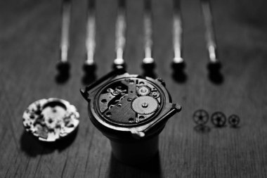 Saatçi atölyesindeki mekanik saatleri tamir ediyor.