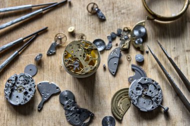 Saatçi atölyesindeki mekanik saatleri tamir ediyor.