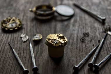 Saatçi atölyesindeki mekanik saatleri tamir ediyor.