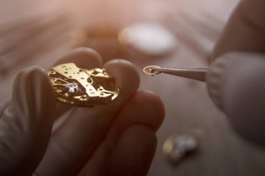 Saatçi atölyesindeki mekanik saatleri tamir ediyor.