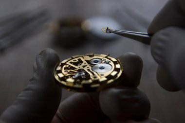 Saatçi atölyesindeki mekanik saatleri tamir ediyor.