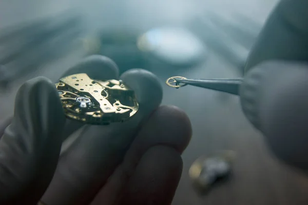 Saatçi atölyesindeki mekanik saatleri tamir ediyor.