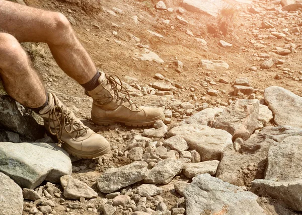 Military boots on the man's feet, desert, rocks,