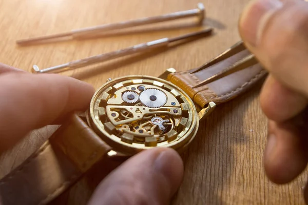 時計職人は工房で機械式時計を修理しています — ストック写真