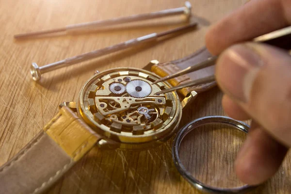 時計職人は工房で機械式時計を修理しています — ストック写真