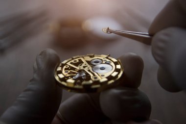 Saatçi atölyesindeki mekanik saatleri tamir ediyor.