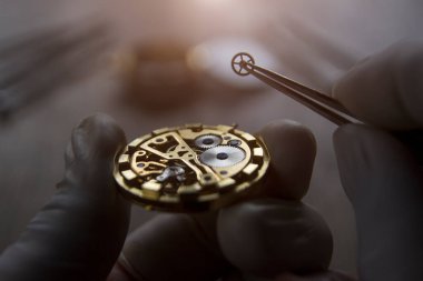 Saatçi atölyesindeki mekanik saatleri tamir ediyor.