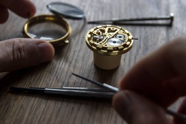 Saatçi atölyesindeki mekanik saatleri tamir ediyor.