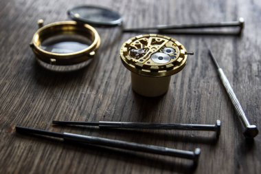 Saatçi atölyesindeki mekanik saatleri tamir ediyor.