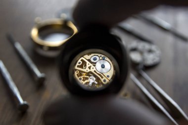 Büyüteç, saatçi atölyesindeki mekanik saatleri tamir ediyor.