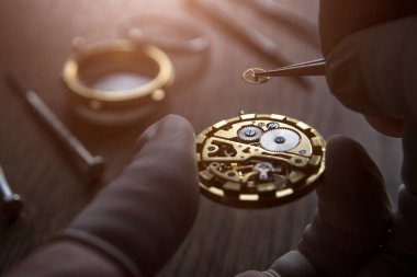 Saatçi atölyesindeki mekanik saatleri tamir ediyor.