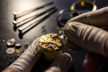 Saatçi antika bir otomatik saati tamir ediyor..