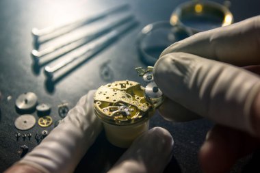 Saatçi antika bir otomatik saati tamir ediyor..