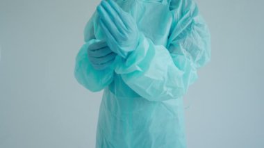 Doktor koruyucu eldiven giyer, koruyucu kıyafet giyer.