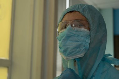 Hastanede koruyucu kıyafetli yorgun bir doktor.