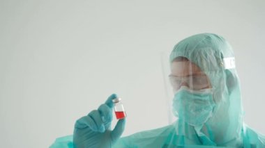 İlaç geliştirme süreci, koruyucu giysili bir doktor ampul tutuyor.