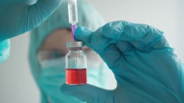 İlaç geliştirme süreci, koruyucu giysili bir doktor ampul tutuyor.