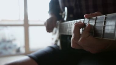 Erkek eli, gitar çalan bir adam.