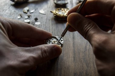 Bir saatçi antika bir otomatik saati tamir ediyor..