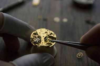 Bir saatçi antika bir otomatik saati tamir ediyor..