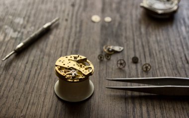 Bir saatçi antika bir otomatik saati tamir ediyor..