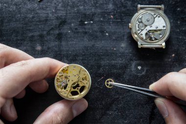 Saatçi mekanik saatleri ve vitesi tamir ediyor.