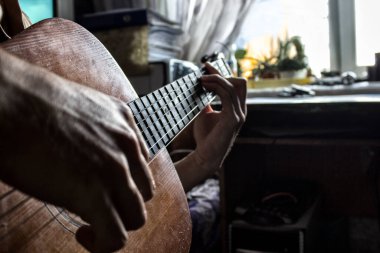 Adam evde gitar çalıyor.