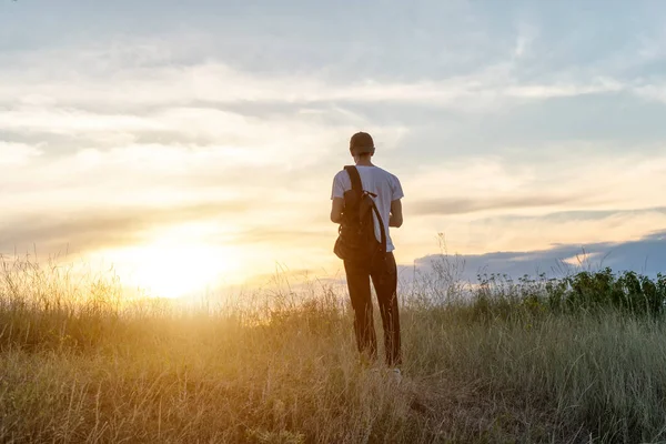 Хлопець стоїть на горі, милуючись заходом сонця — стокове фото