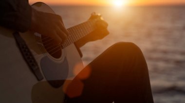 Genç adam akustik gitarla çalıyor.