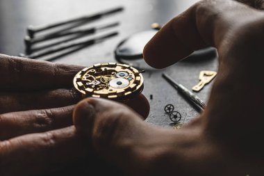 Saatçi mekanik kol saati takıyor.