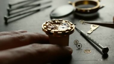 Saatçi mekanik kol saati takıyor.