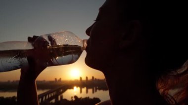 Kız şişeden su içiyor.