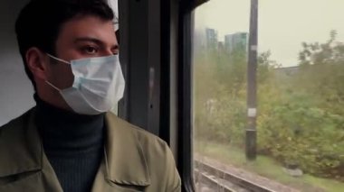 Yorgun gözlü genç adam pencereden dışarı bakarak tren yolculuğuna çıkıyor.