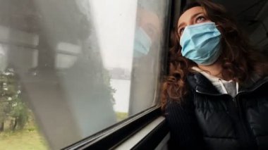 Yorgun bakışlı genç kız pencereden dışarı bakarak tren yolculuğuna çıkıyor.