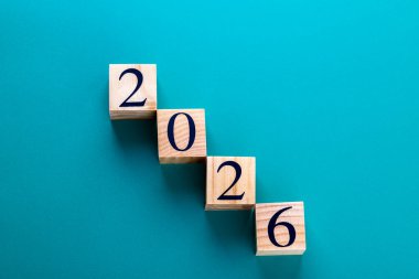 Ahşap blokların yatay çekimi mavi arkaplanda 2026 'yı oluşturuyor. Uzayı kopyala İlerleme kavramı, hedefler ve kişisel büyüme