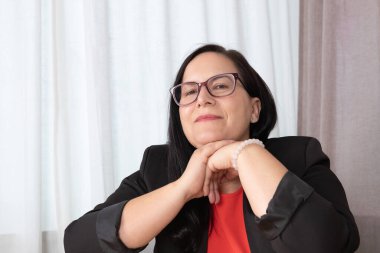 Sakin ve gülümseyen bir yüz ifadesi olan bir kadının portresi, elleri çenesinin altında katlanmış, derin düşüncelere dalmış bakışlar, iç gözlem ya da duygusal liderlik için ideal. Kişisel yansıma kavramı