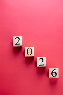 2026 numaralı tahta küpleri kırmızı zemin üzerinde çapraz düzenleme, negatif uzay ile dikey yönelim. Uzayı kopyala Yeni yıl ve planlama kavramı