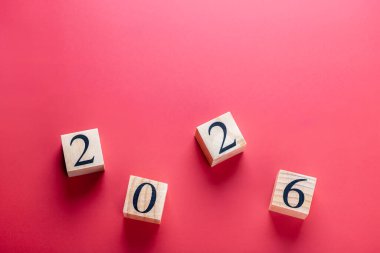 Ahşap bloklar kırmızı zemin üzerine dağılmış 2026 numarayı oluşturuyor, yatay çekim. Yeni yılın ve gelecekteki vizyonun kavramsal görüntüsü. Uzayı kopyala Yeni yıl ve gelecek vizyon kavramı