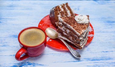 Kremalı ekşi pasta ve kırmızı bardakta taze kahve.