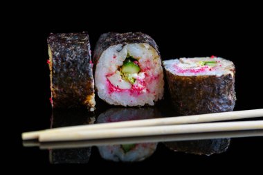 Suşi rulosu koyu bir arkaplanda izole edilmiş..