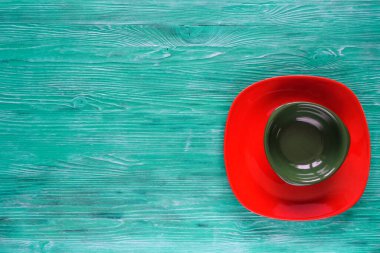 Yeşil ahşap zemin üzerinde boş kırmızı tabak.