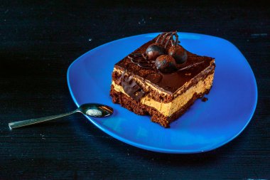 Tahta arka planda mavi bir tabakta bir parça çikolatalı pasta..