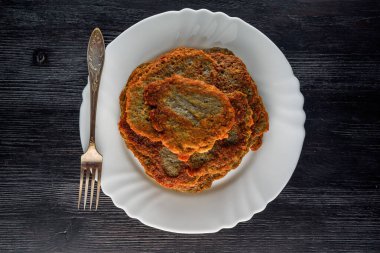 Tahta bir taşrada, beyaz bir tabakta bir yığın patatesli krep.