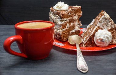Kremalı ekşi pasta ve kırmızı bardakta taze kahve.