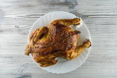 Kızarmış tavuk, ahşap bir arka planda beyaz bir tabakta.