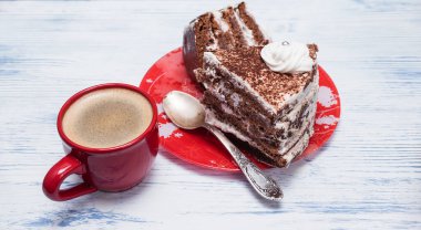 Kremalı ekşi pasta ve kırmızı bardakta taze kahve.