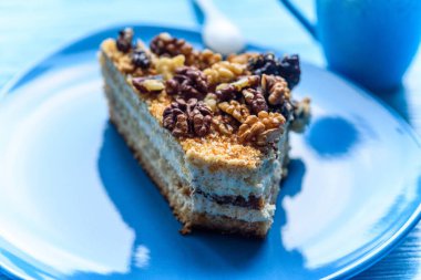 Cevizli kek dilimi, ahşap arka planda, turkuaz bir plakaya yakın plan çekilmiş..